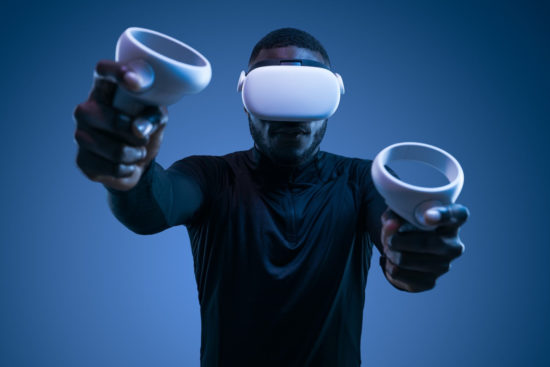 Focused black man playing video game with joysticks in VR goggles